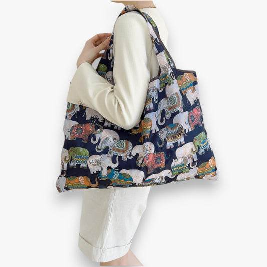 A model holding a navy nylon tote bag with a colourful elephant pattern on the shoulder.