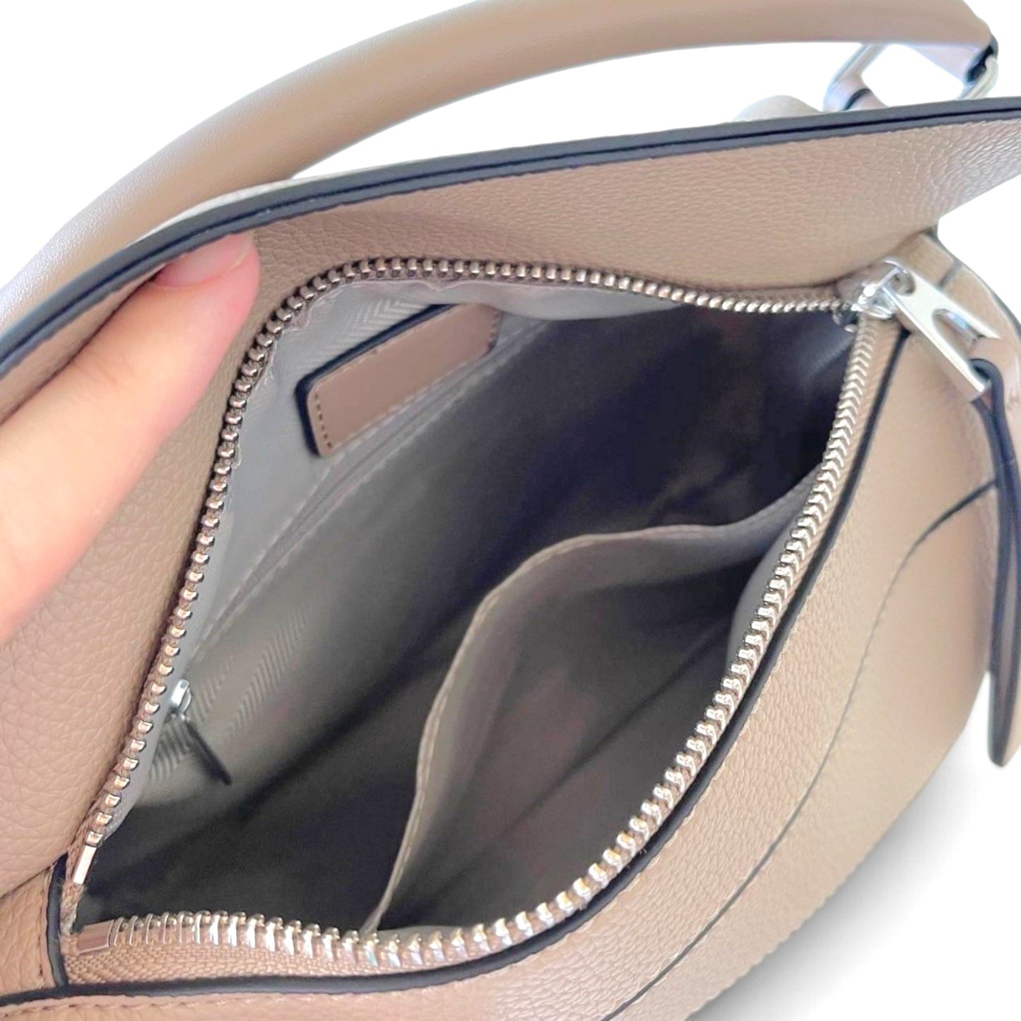 Interior of an Amy handbag in Sand, featuring two pockets and soft fabric lining.