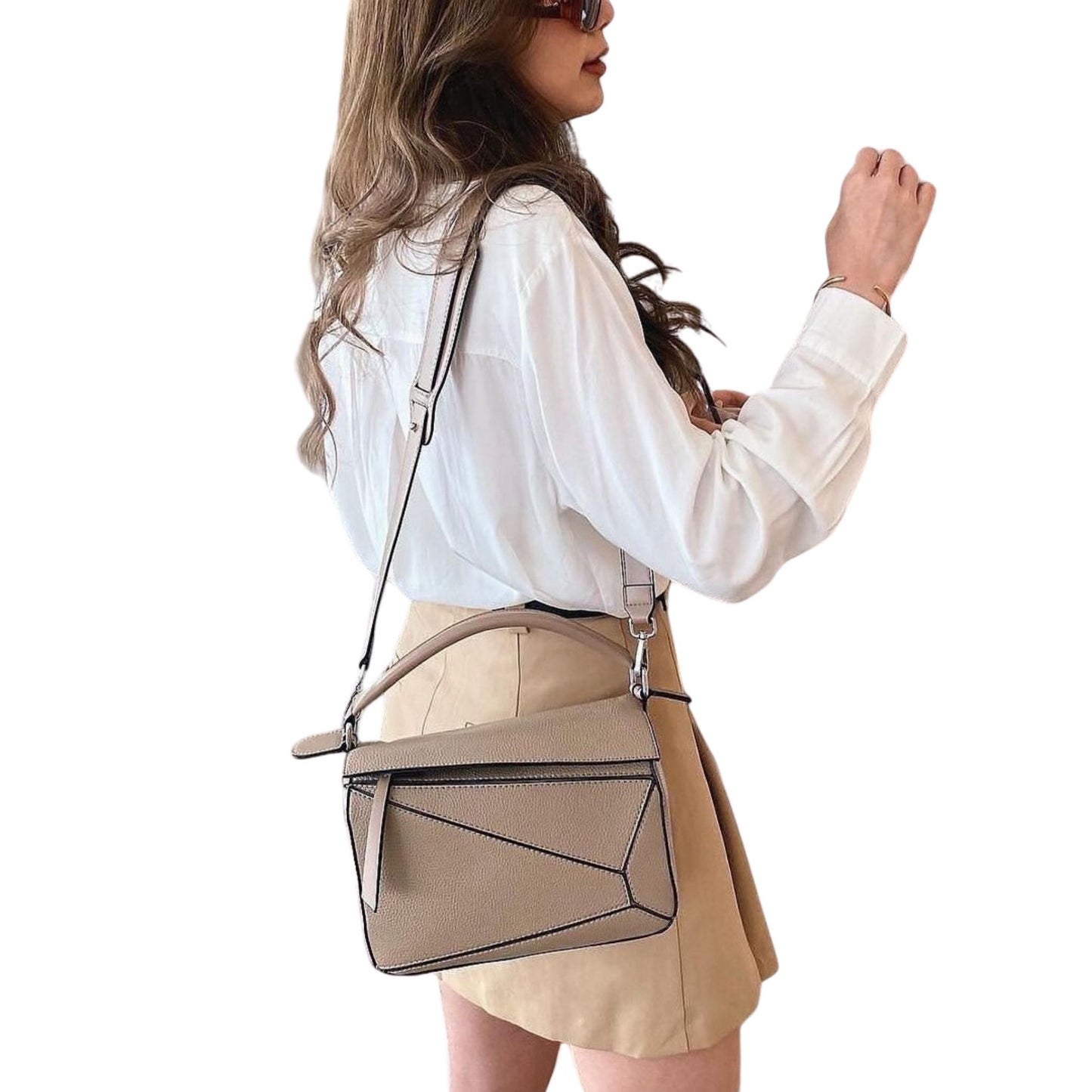 A woman wearing a beige handbag over her shoulder with an adjustable strap featuring a wide shoulder pad.