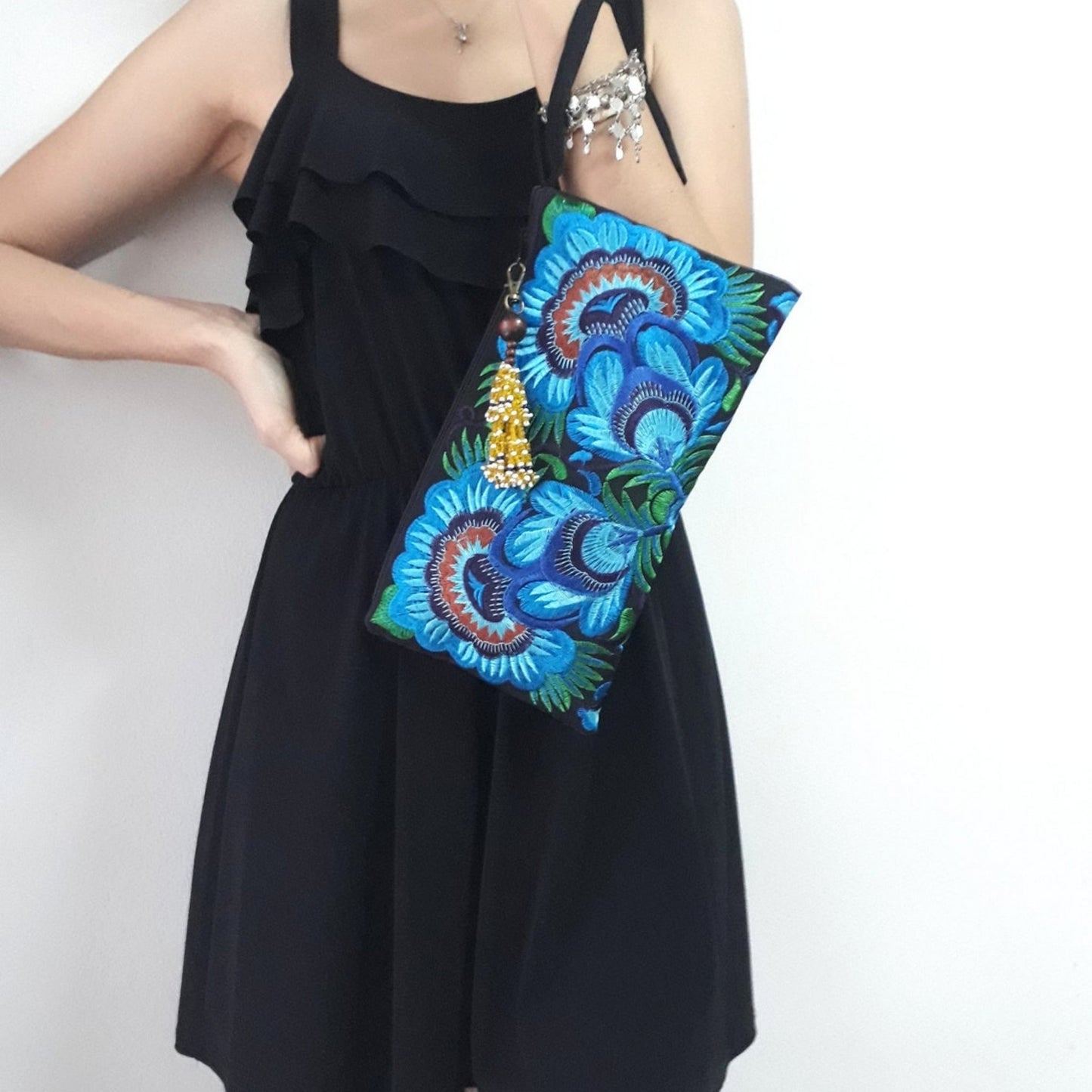 Handmade embroidered large wristlet bag with blue floral design carried by a model.