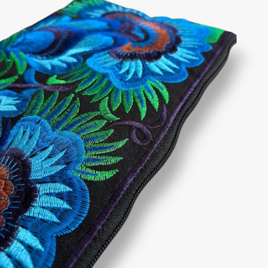 Close-up of an artisan embroidered wristlet with bold blue and green floral design.