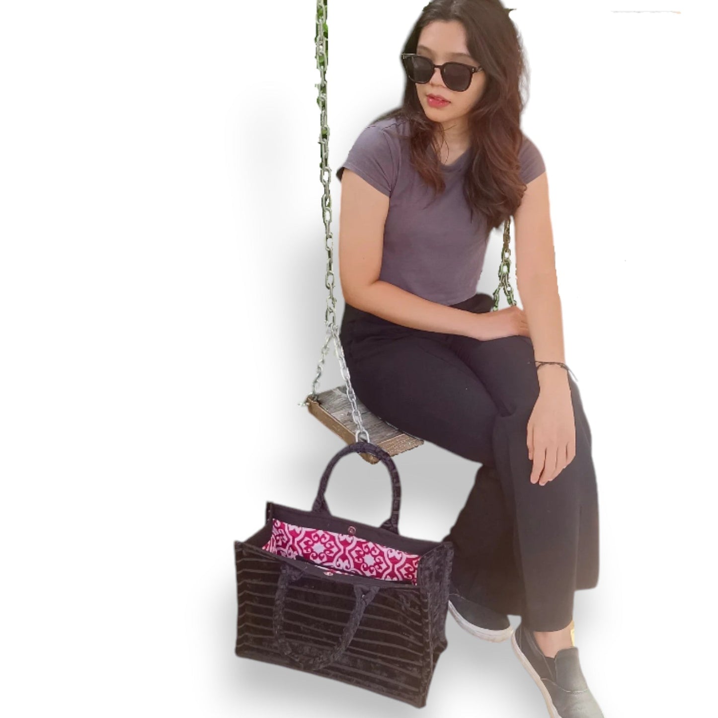 A woman sits on a swing with a black chenille handmade book tote, showing the bag's size and style.