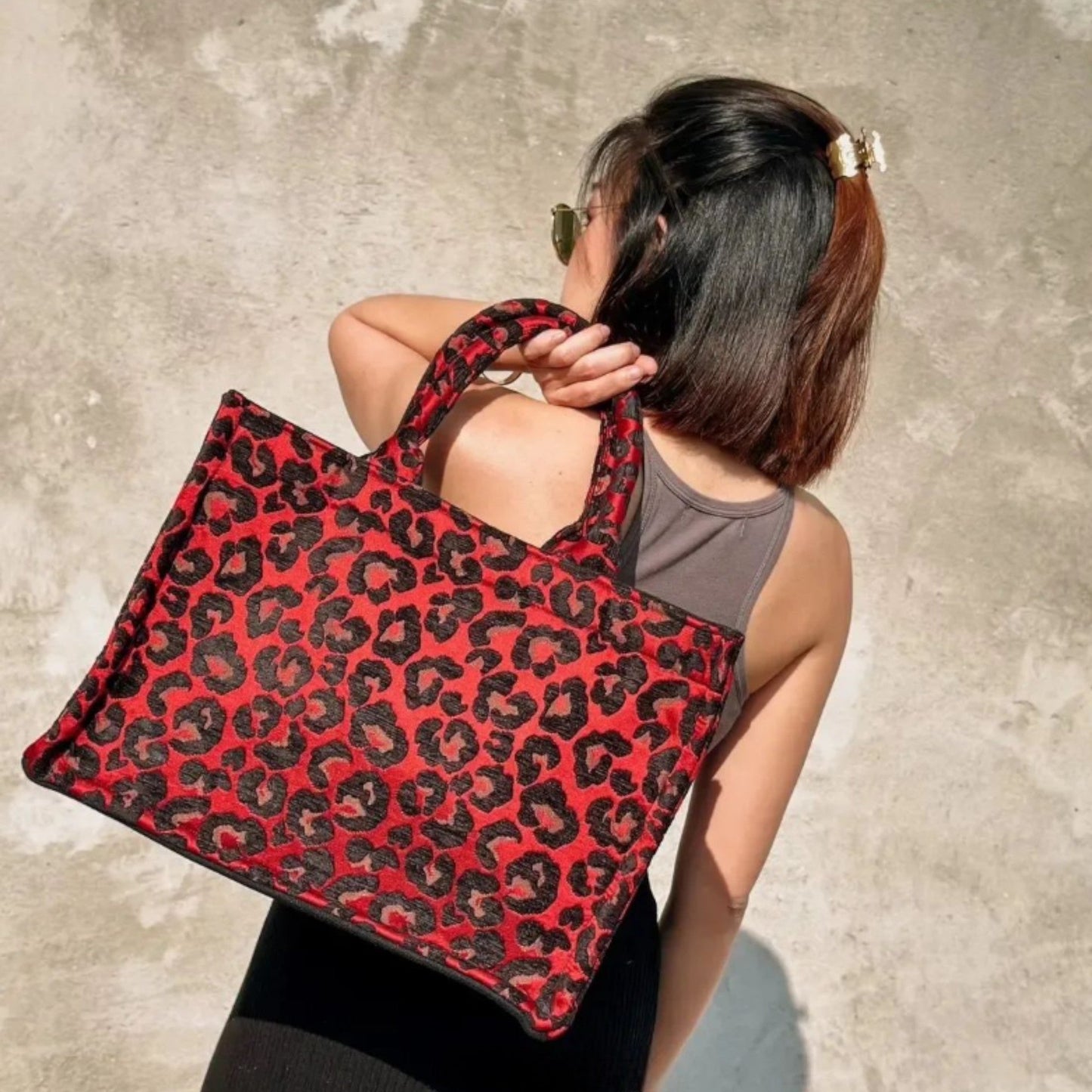 Model wearing a handmade leopard print book tote bag over the shoulder, showcasing its spacious design.