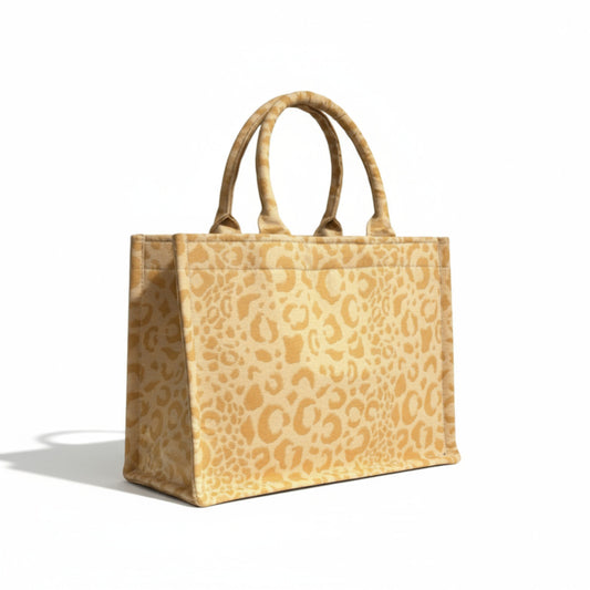 Side angle view of a yellow leopard handmade tote with soft double handles and a structured design.