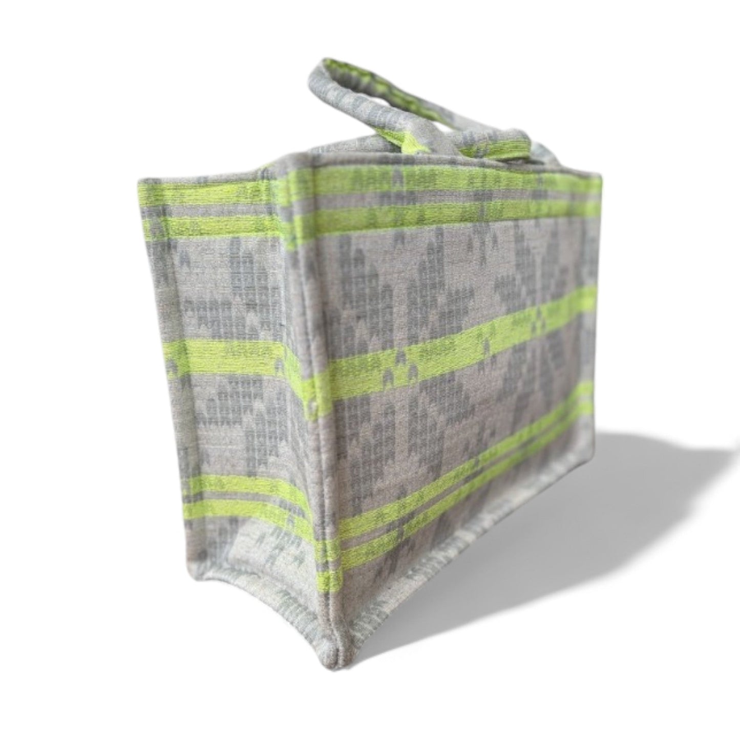 Close-up side view of a tote bag with neon green stripes on a light grey star-patterned fabric.