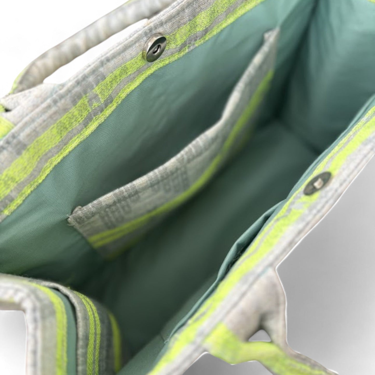 Interior of a tote bag with green lining, slip pockets, and a magnetic closure.