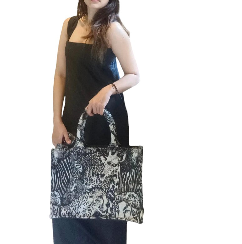 Woman carries the handles of a tote with a wild animal print, highlighting its versatile everyday use.