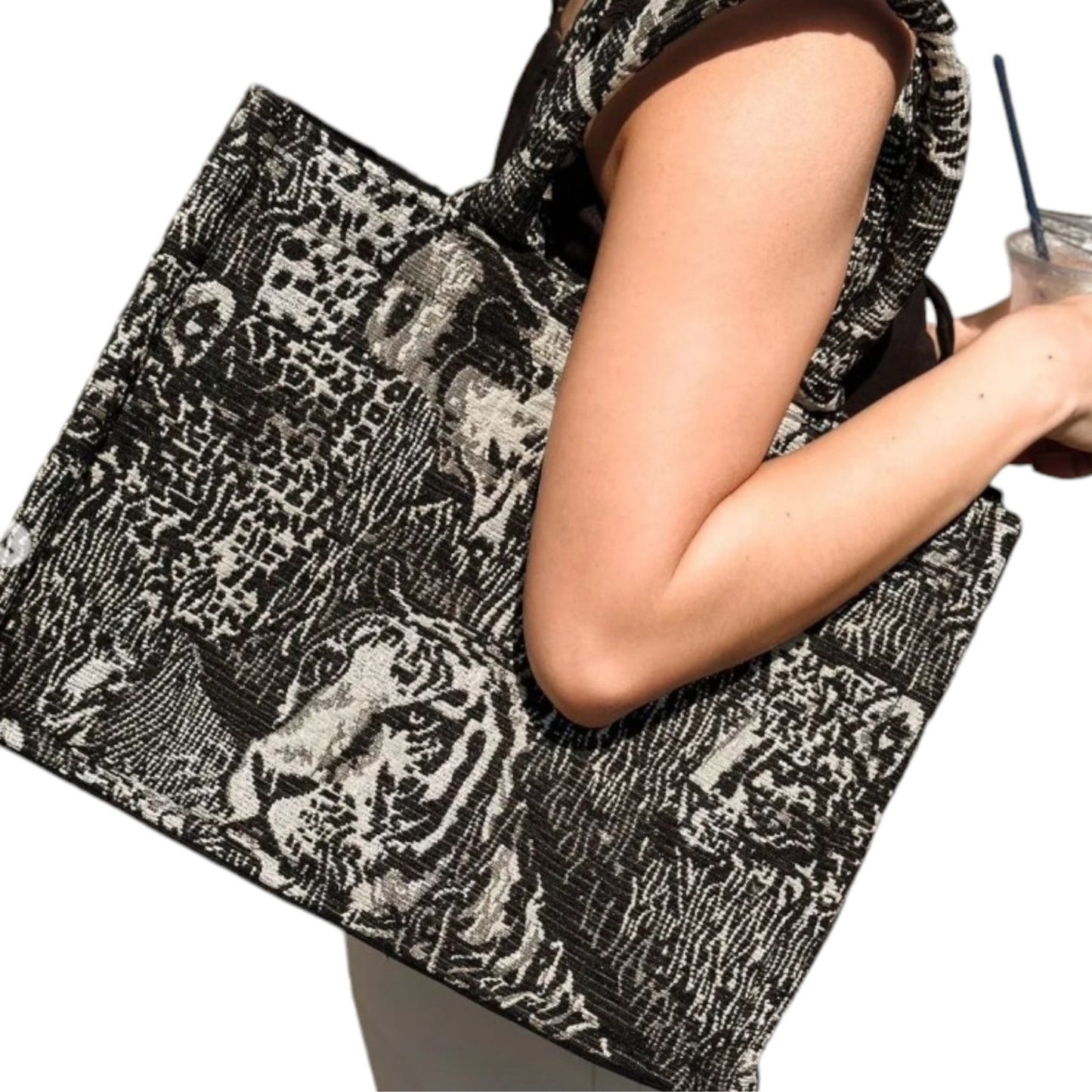 A model wearing a white and black book tote with wild animal prints on her shoulder, showing its luxurious design.