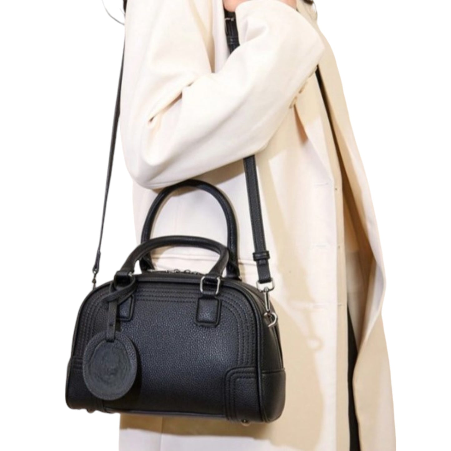 A person wearing Celeste, a black vegan leather bowling bag over her shoulder, using an adjustable, detachable strap.