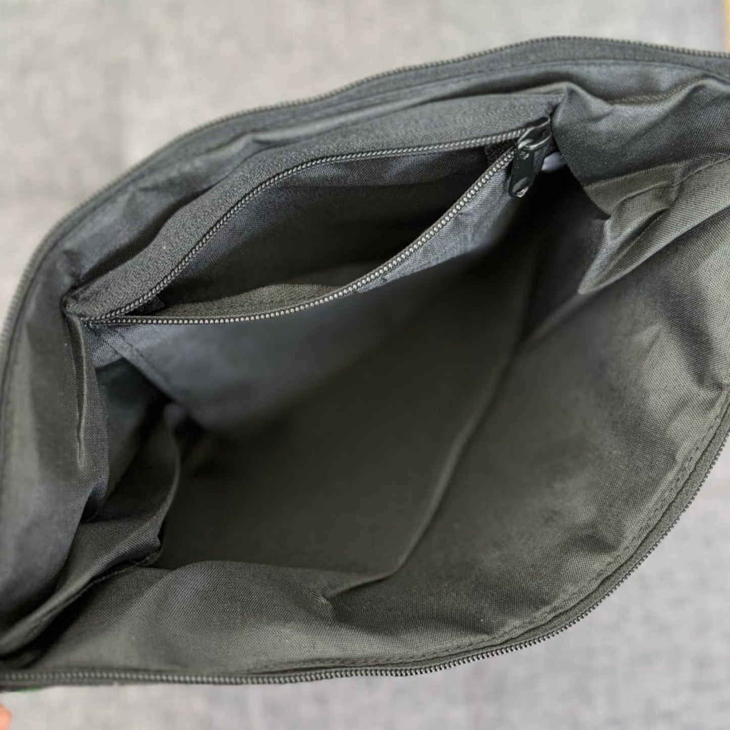 Interior of a bag with black fabric lining and a zip pocket.