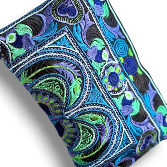 Close-up of a blue and green embroidered fabric with intricate bird & floral patterns.