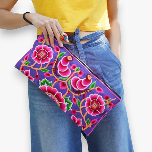 Woman holding Hmong peony embroidered clutch bag in pink and periwinkle.