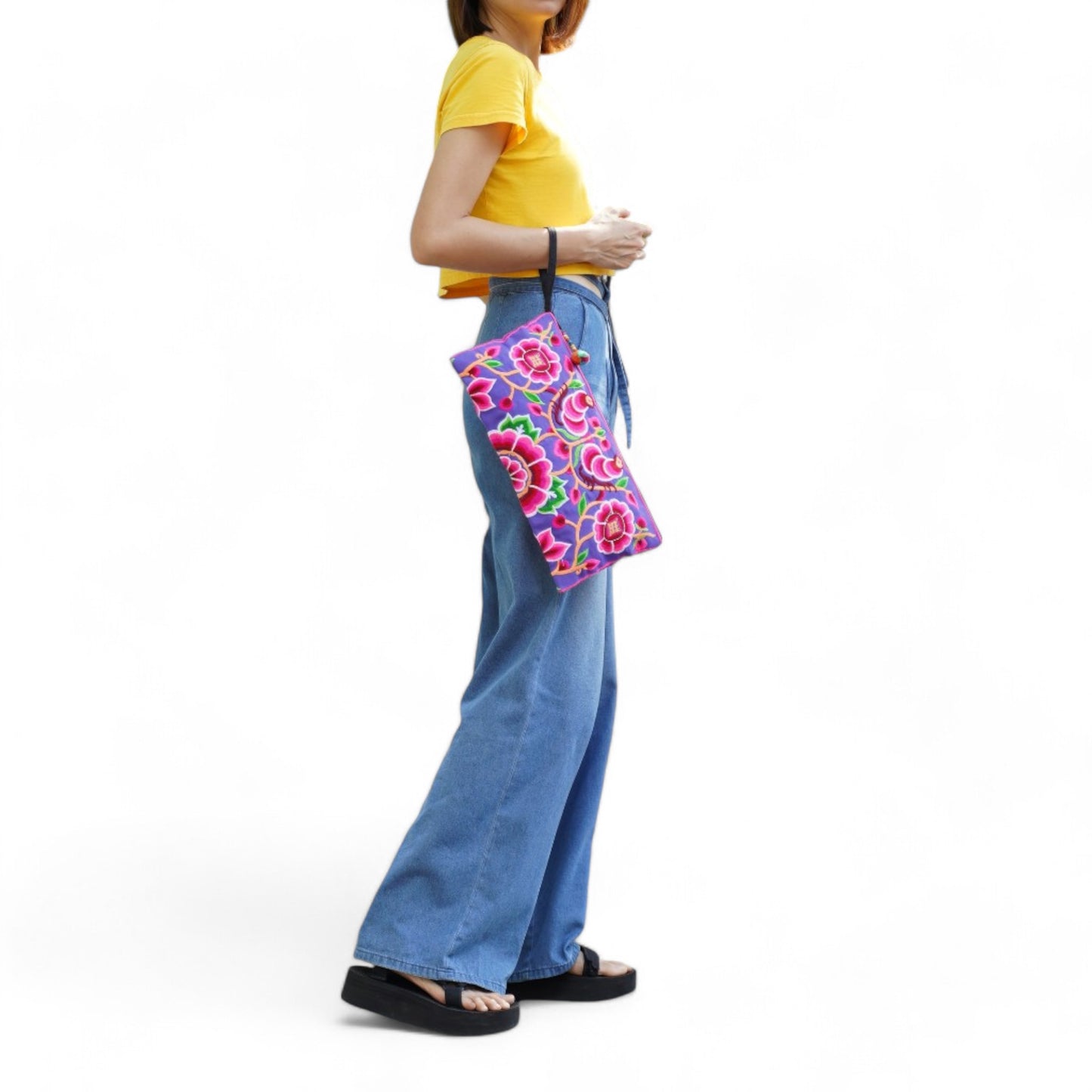 A model with a pink peony clutch bag embroidered in Hmong style on her wrist, dressed casually.