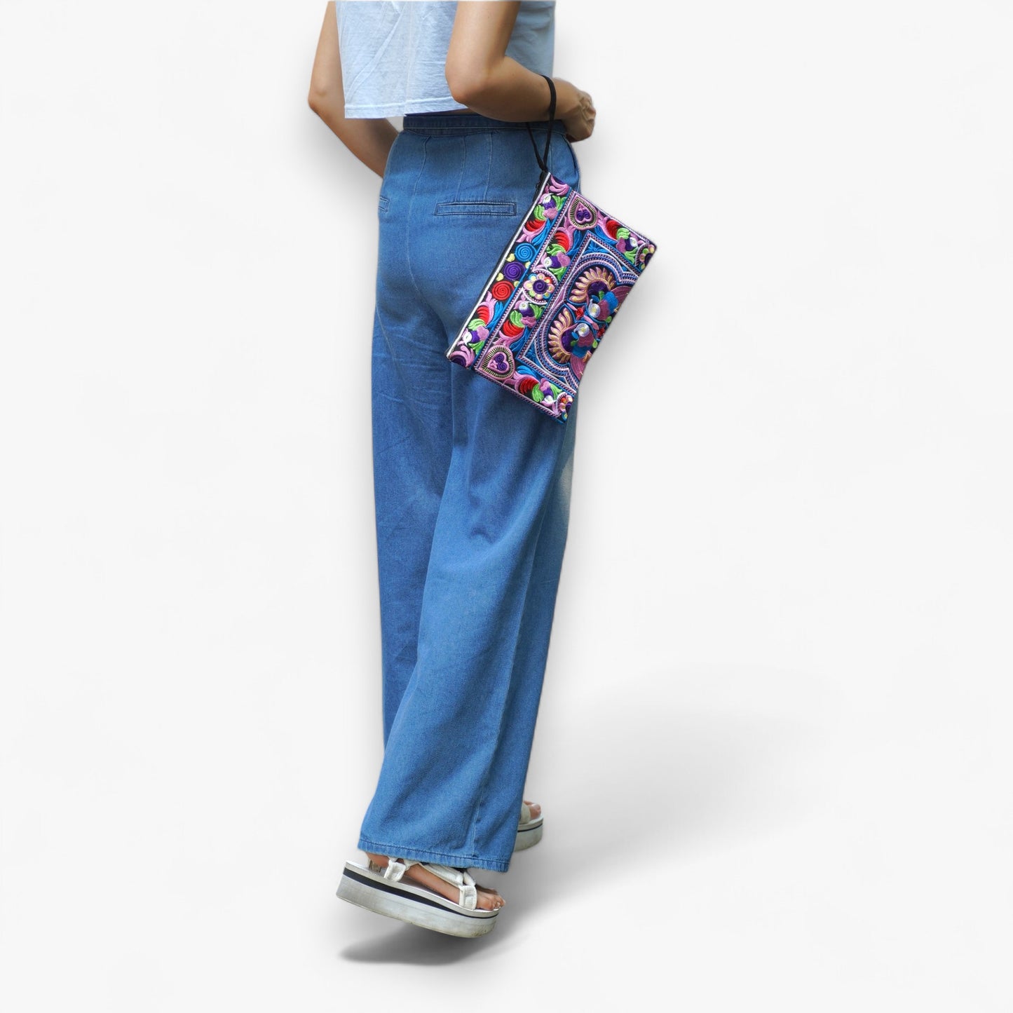 A model carrying a colourful embroidered oversized clutch bag on her arm with a strap.