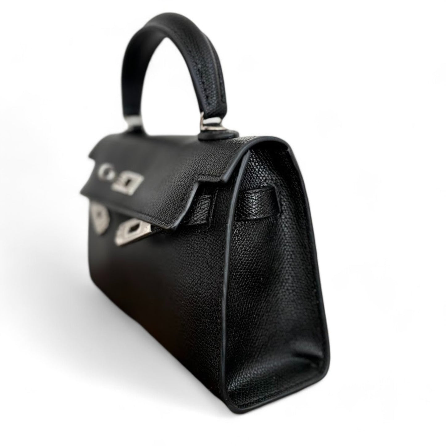 Angle view of black mini top-handle bag with silver hardware, side strap & closed flap.