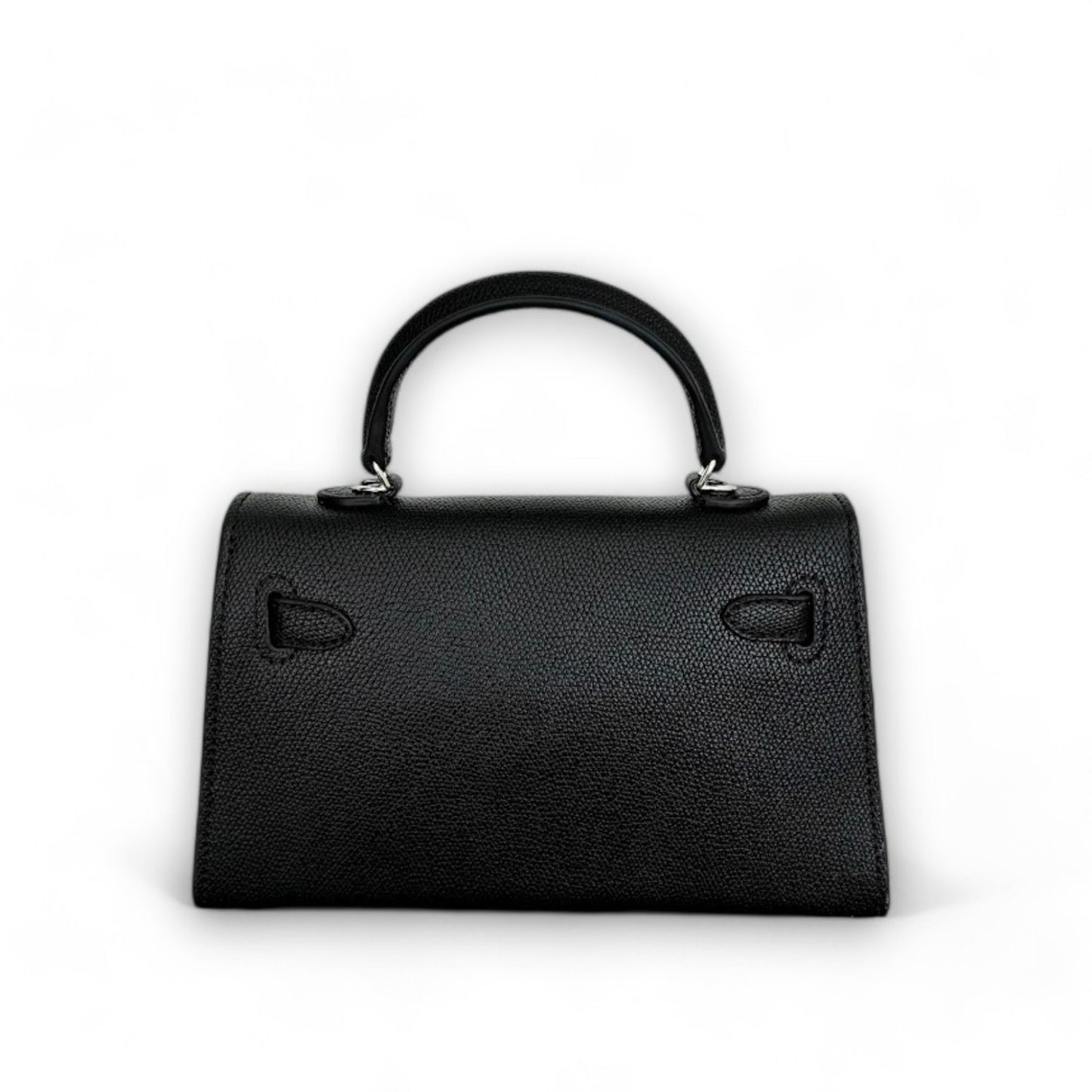 Back view of a black, structured, trapezoid-shaped mini top-handle bag.
