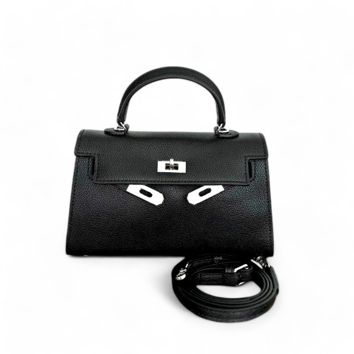 Black mini top-handle bag with silver hardware, closed flap & adjustable shoulder strap shown beside the bag.