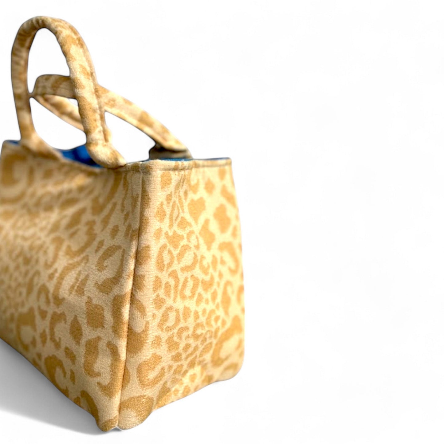 Side view of a handmade yellow leopard fabric mini tote bag with blue interior.