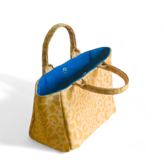 Handmade yellow leopard print fabric bag with blue lining seen from the top.