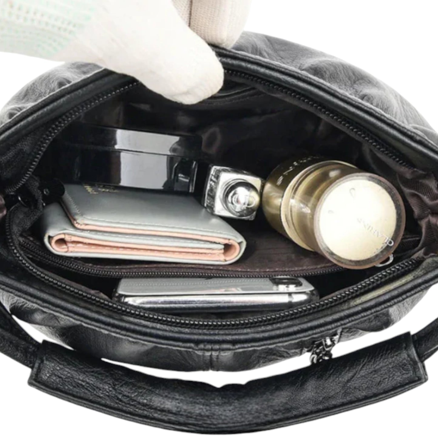 Interior of a black handbag showing personal belongings inside. It has a zip closure and a zip pocket.