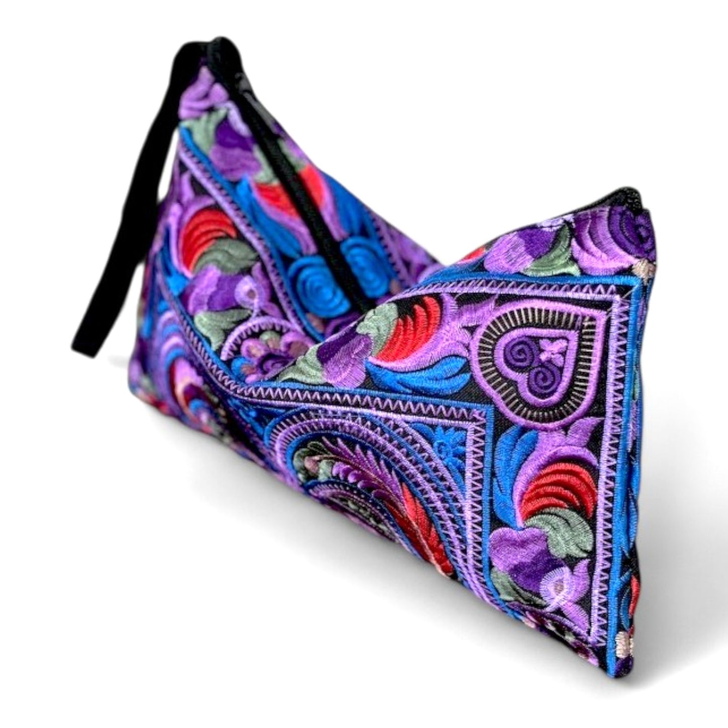 Angle view of a purple and blue, bird and floral patterns embroidered pouch with a black strap.
