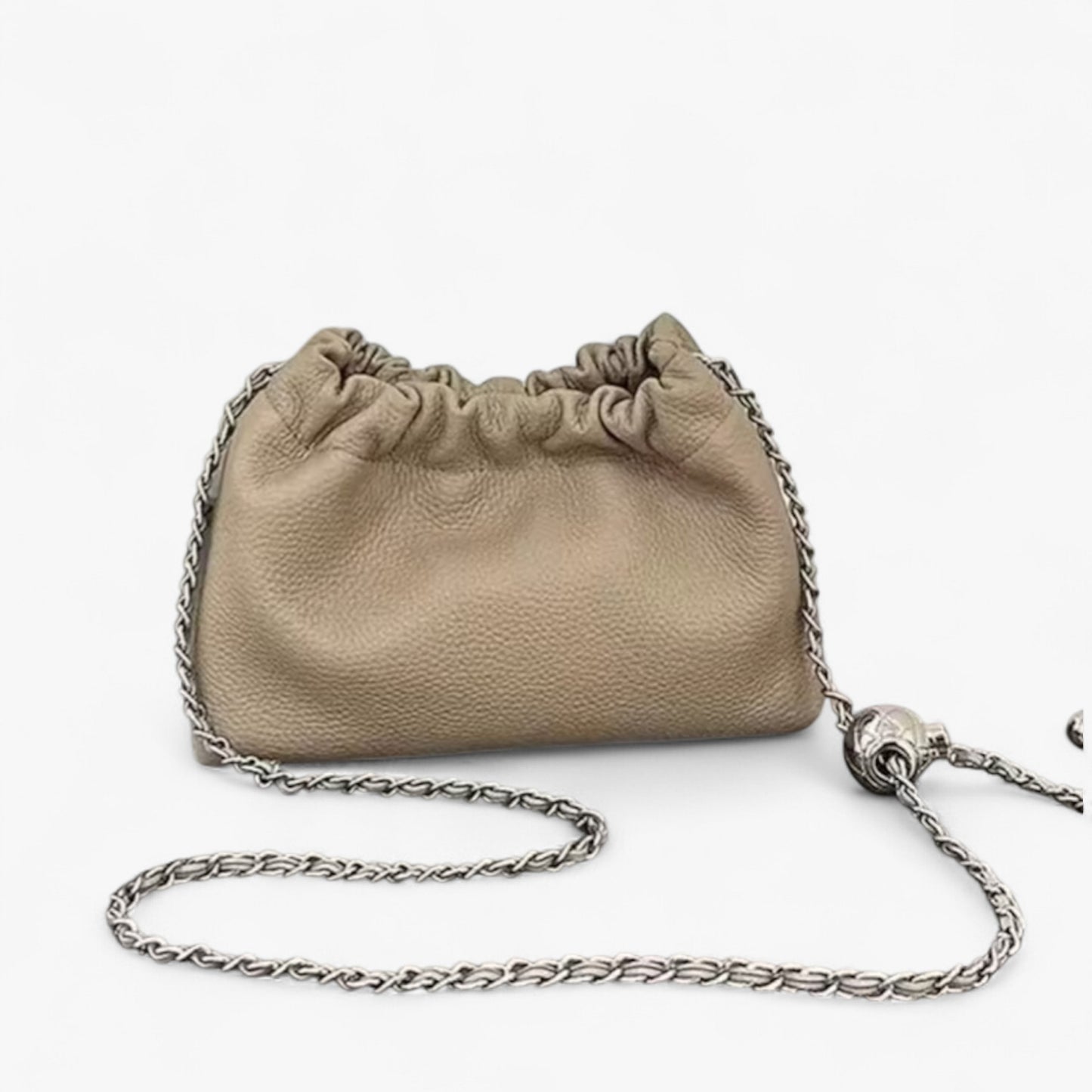 A beige leather handbag with a top ruched detail and a silver chain strap.