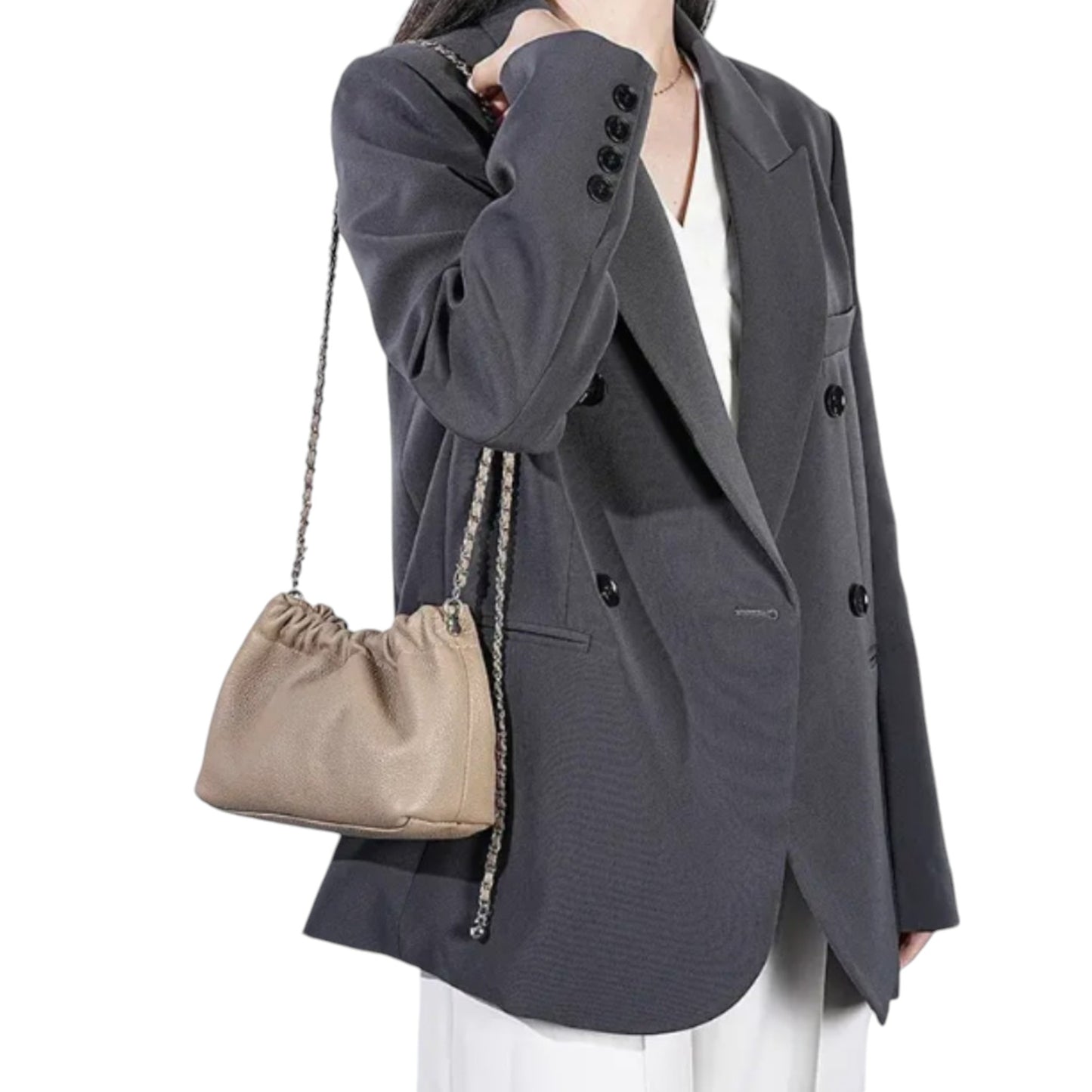 A woman carries a beige handbag with silver chain on her shoulder