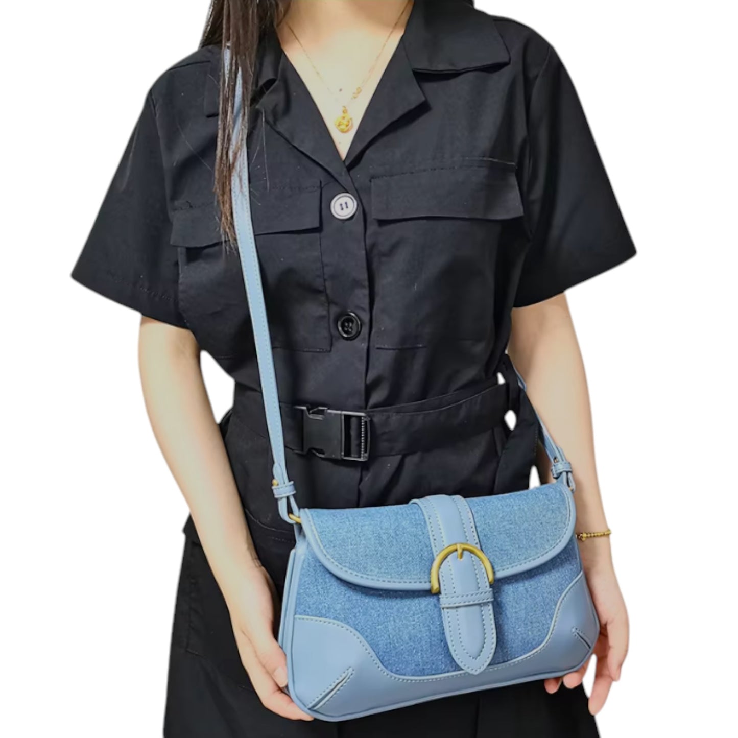 A woman carries a blue denim bag with leather trim and brass-tone details across her body.
