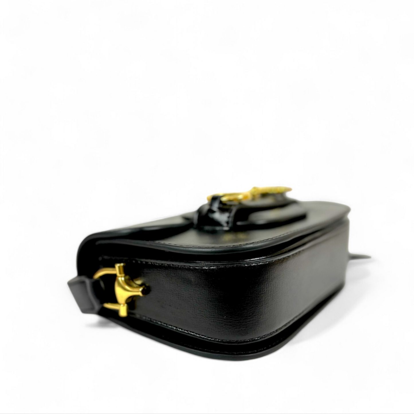 A bottom view of a black handbag with gold hardware.