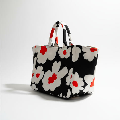 Shopper Bag Daisy Pop in black with bold white daisies and orange accents, angled view with handles.