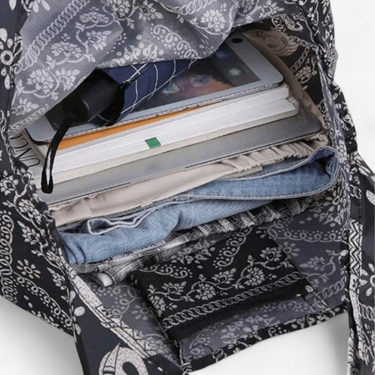 An open, dark brown and white elephant pattern tote bag containing a laptop, books, and personal belongings.