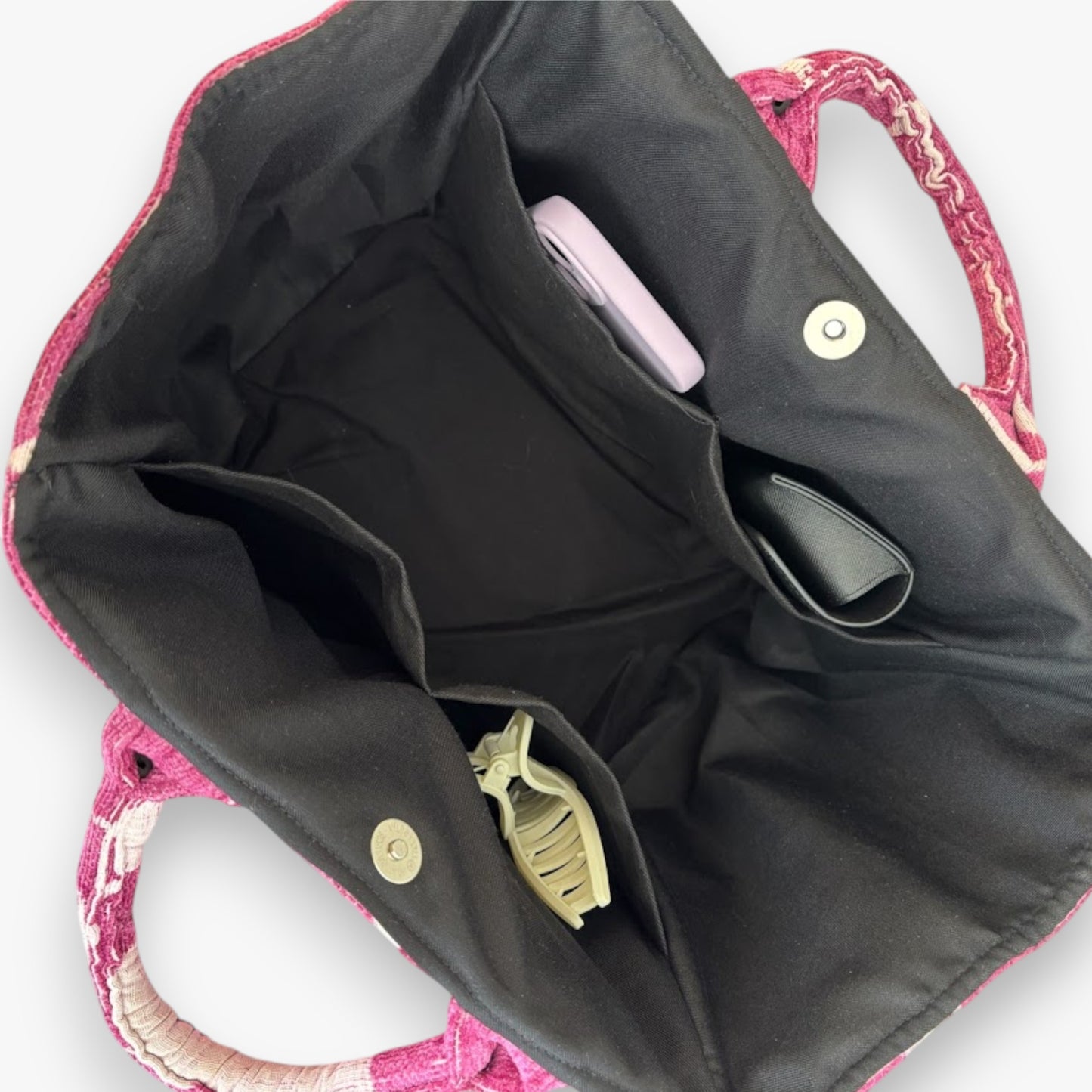 An open magenta floral tote bag showing black linging, roomy interior, multiple pockets, and magnetic closure.