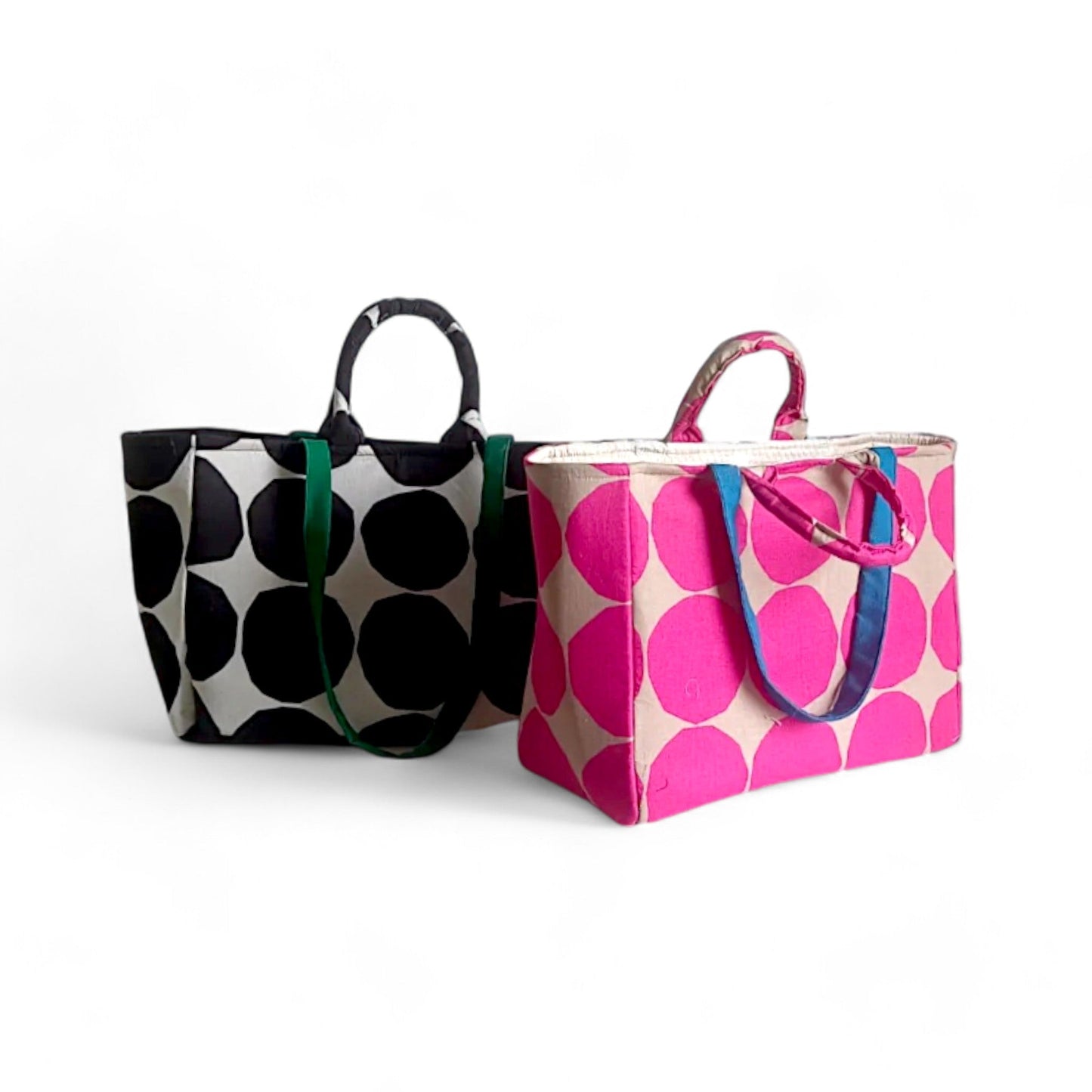 Two polka-dot shopper bags. The one on the left is black and white, the one on the right is pink and tan.