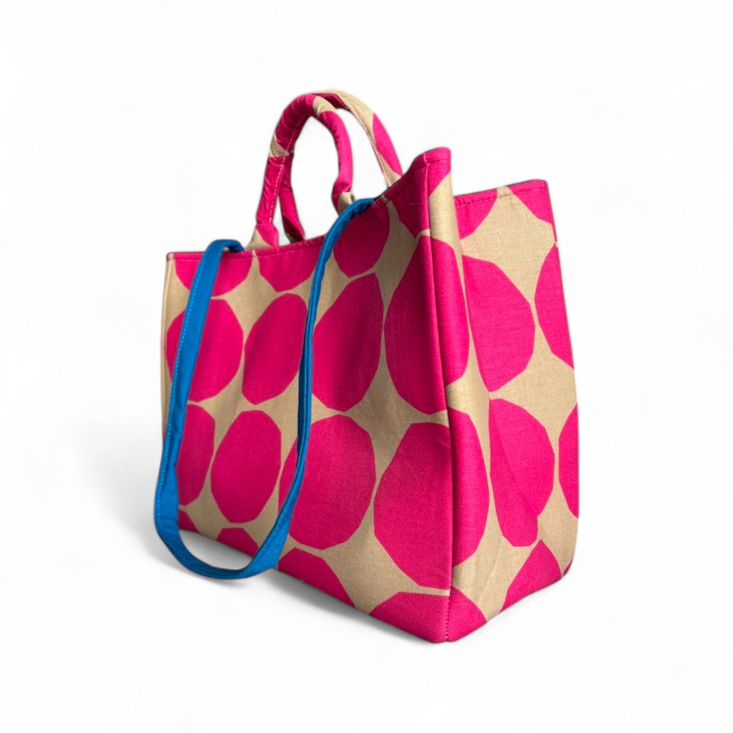 Side view of a hot pink and tan polka dots tote bag with a contrasting blue strap.
