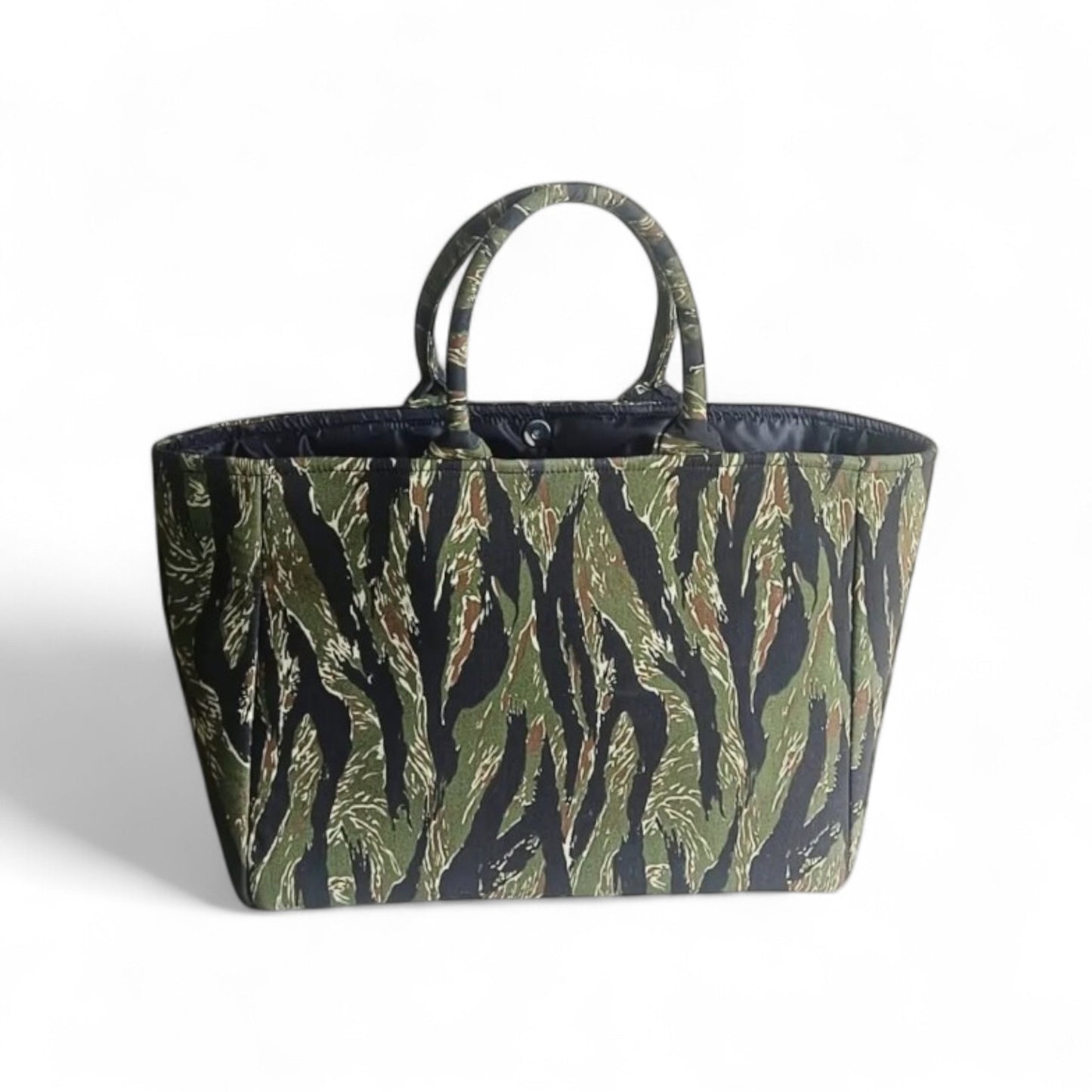 An open tote bag with a jungle green and black camouflage pattern, a magnetic closure and black lining.