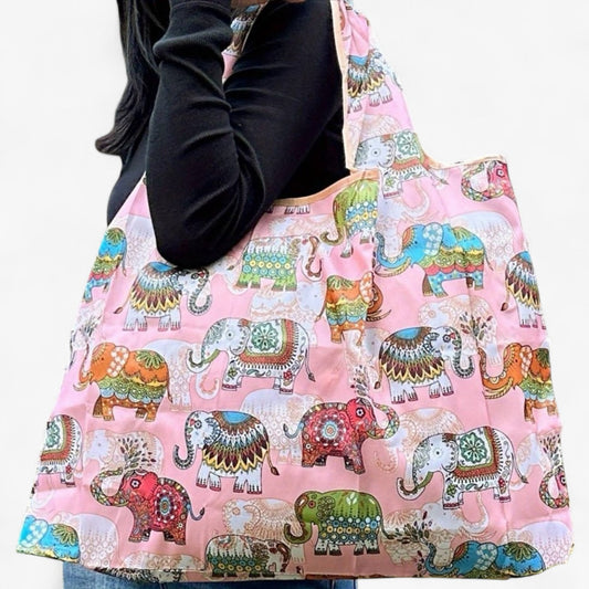 A model carrying a pink nylon tote bag with colourful elephant patterns on the shoulder.