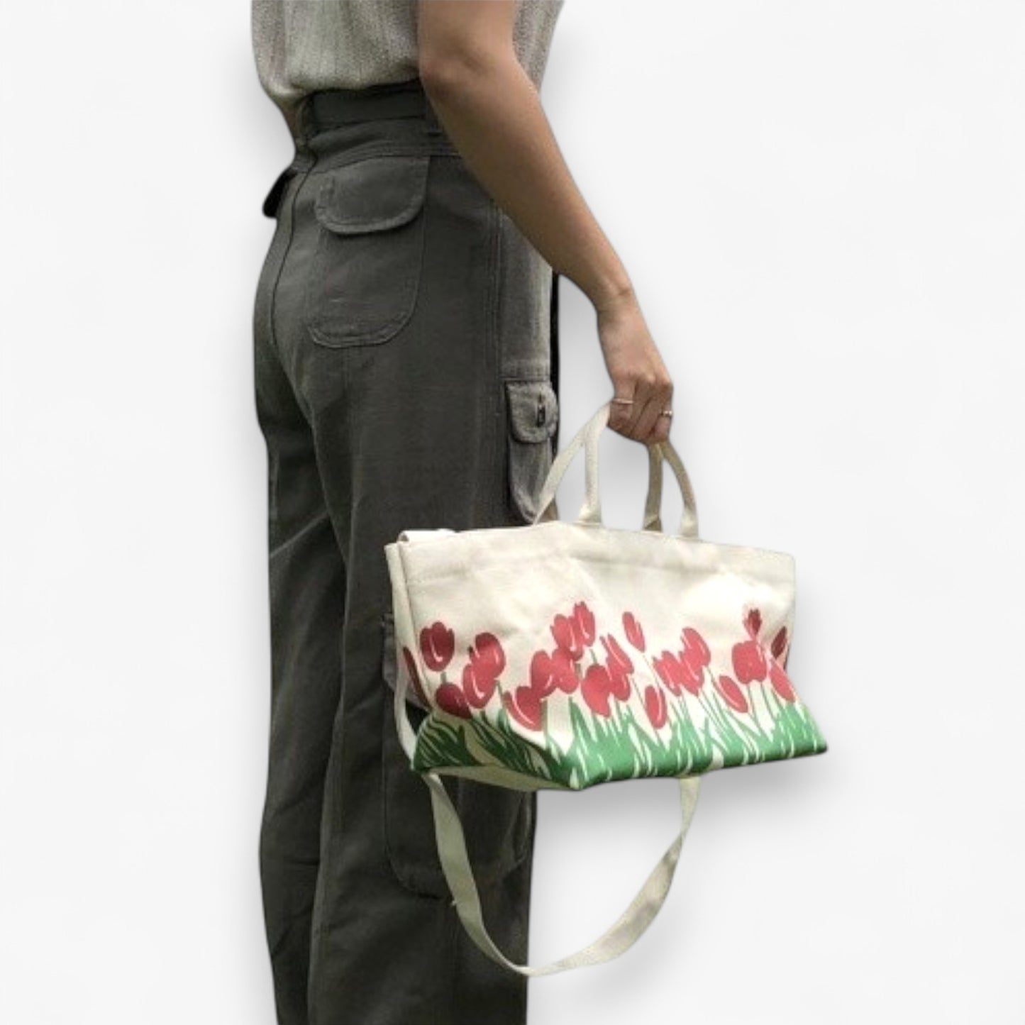 A person is carrying a canvas shopper tote bag with a red tulip design.