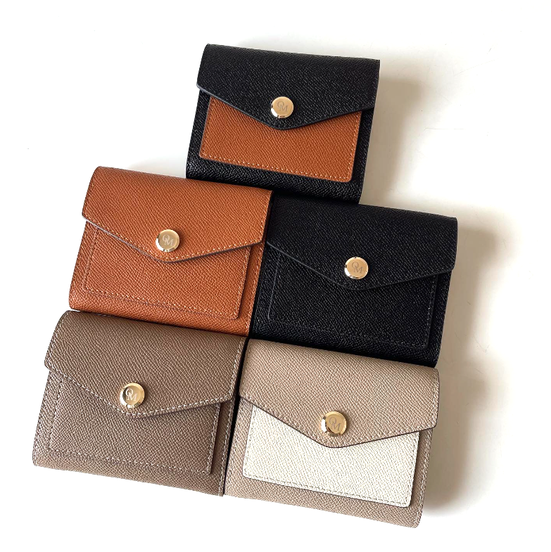 Assorted minimalist leather wallets with envelope flaps and gold snap buttons in a flat lay.