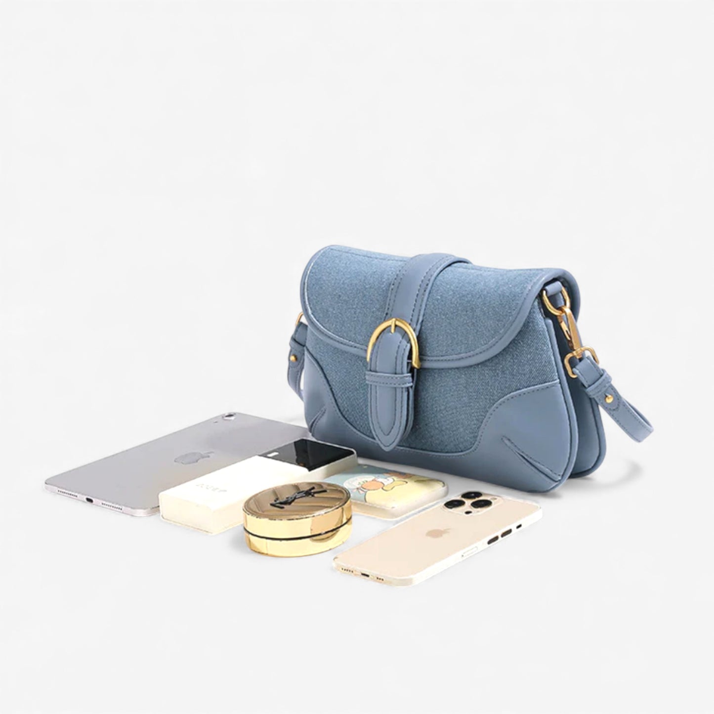 Blue denim handbag with essentials: phone, tablet, and makeup, showcasing its spaciousness.