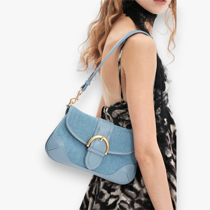 Close-up of a model carrying a stylish blue denim shoulder bag on her shoulder.