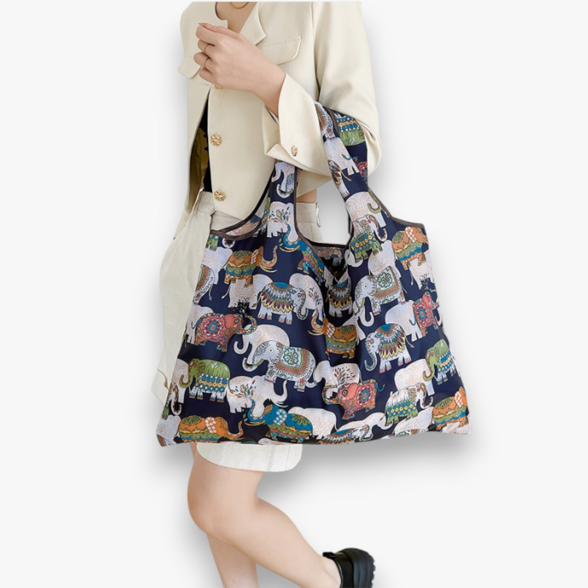 A model carrying a navy nylon tote bag with a colourful elephant pattern in the crook of her arm.