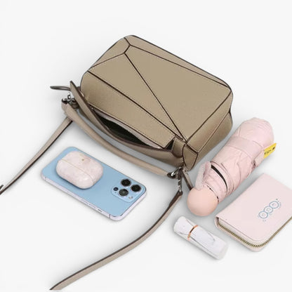 A geometric bag in beige with angular panel design, compact crossbody style for everyday wear.