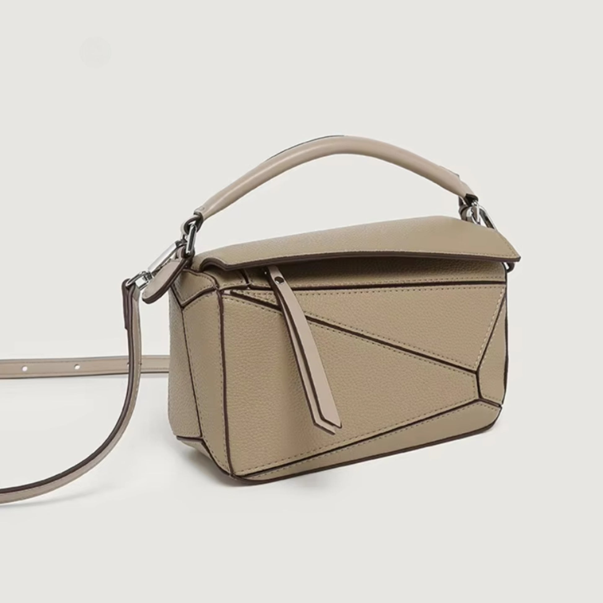 A everyday beige handbag with geometric panels, a zipper pull, top handle, and a crossbody strap.