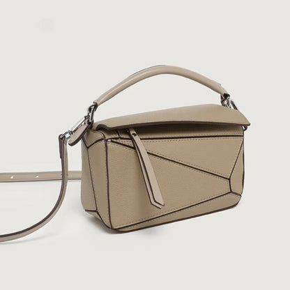 A everyday beige handbag with geometric panels, a zipper pull, top handle, and a crossbody strap.