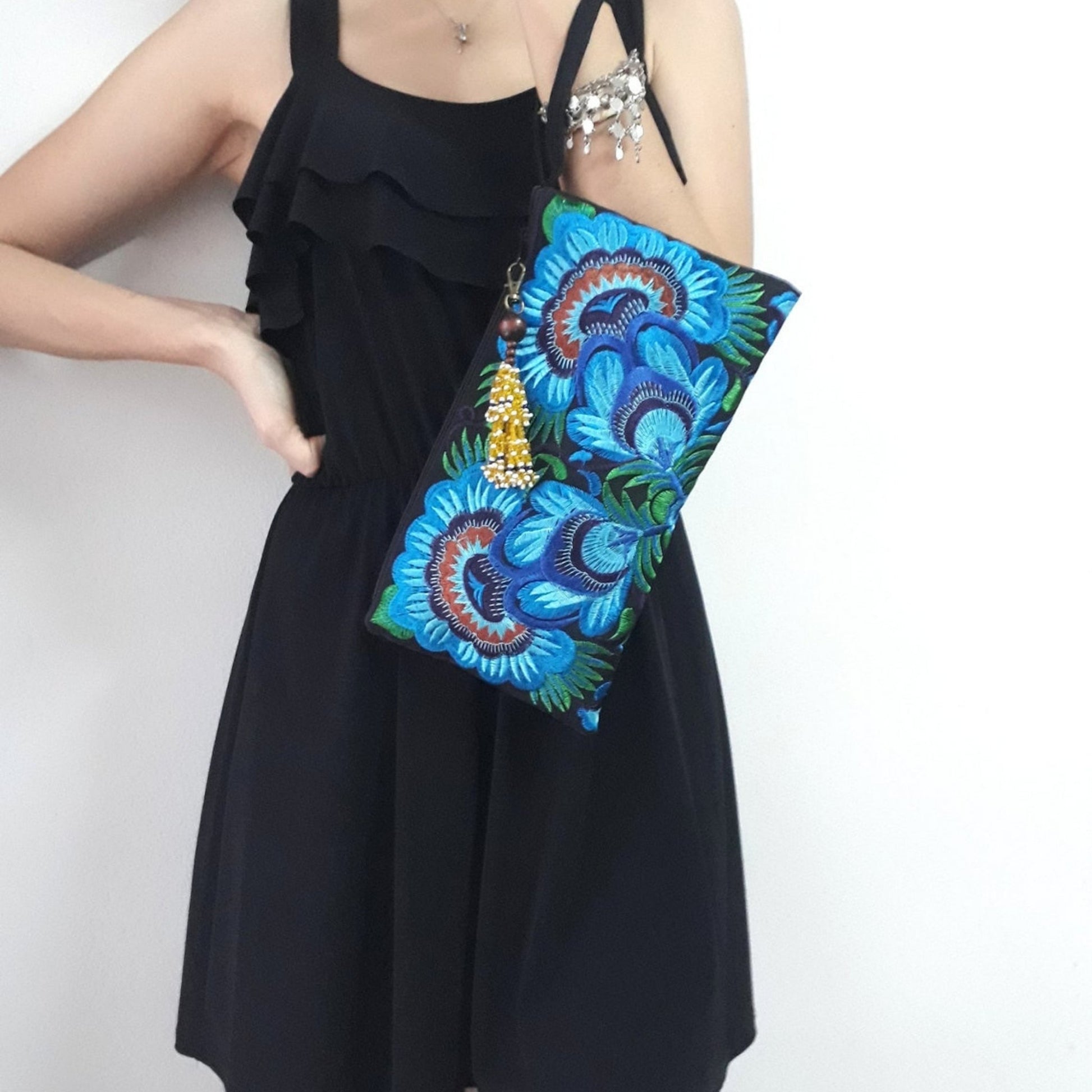 Handmade embroidered large wristlet bag with blue floral design carried by a model.