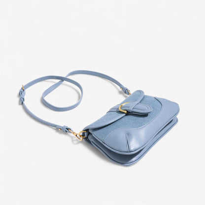 Chic blue saddle bag with a long strap, a must-have accessory for fashion lovers.