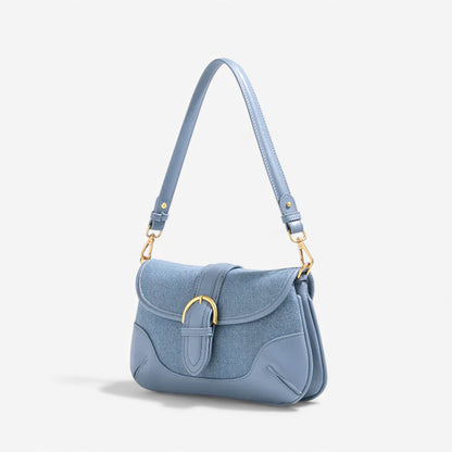 Angle view of a blue denim shoulder bag with gold hardware fashion chic.
