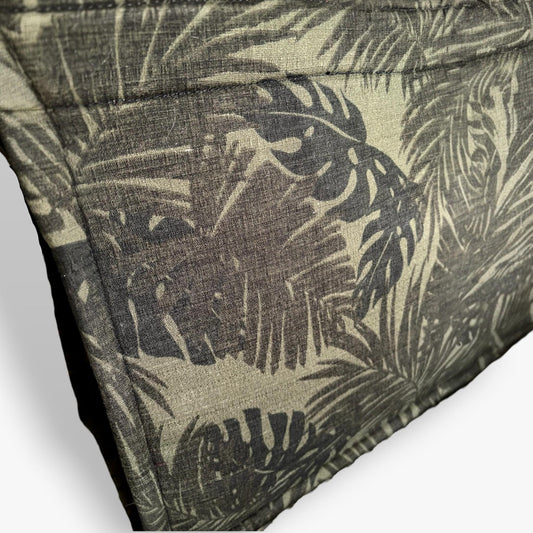 Close-up of a light muted green textured tote bag with dark monstera and palm leaf patterns.