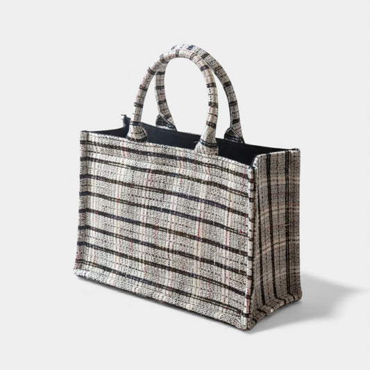 A classic tote bag made with white tweed fabric with black, red, silver and blue threads.