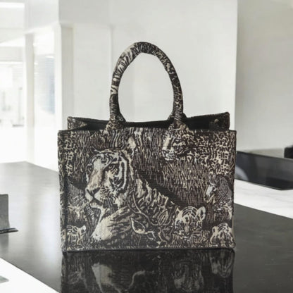 A chic and versatile tote bag with black and beige wild animal pattern sitting on a black counter top.